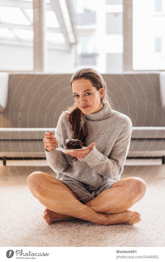 Portrait of woman sitting on floor eating piece of cake pies cakes Seated smiling smile females women Sweet Food sweet foods food and drink Nutrition
