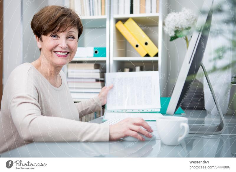 Senior woman working at computer with a cup of coffee females women At Work Coffee learning senior women elder women elder woman old senior woman sitting Seated