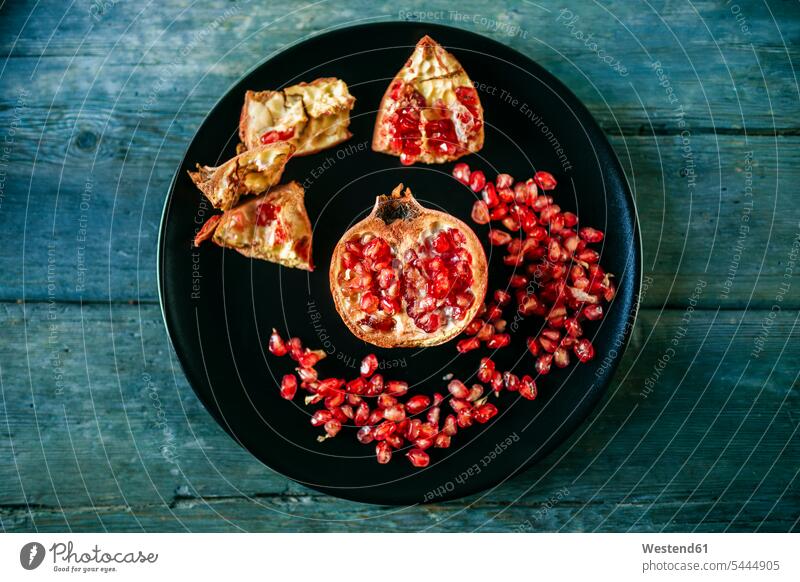 Half of pomegranate and pomegranate seed on black plate nobody red Preparation prepare preparing peeled copy space preparation Freshness fresh healthy eating