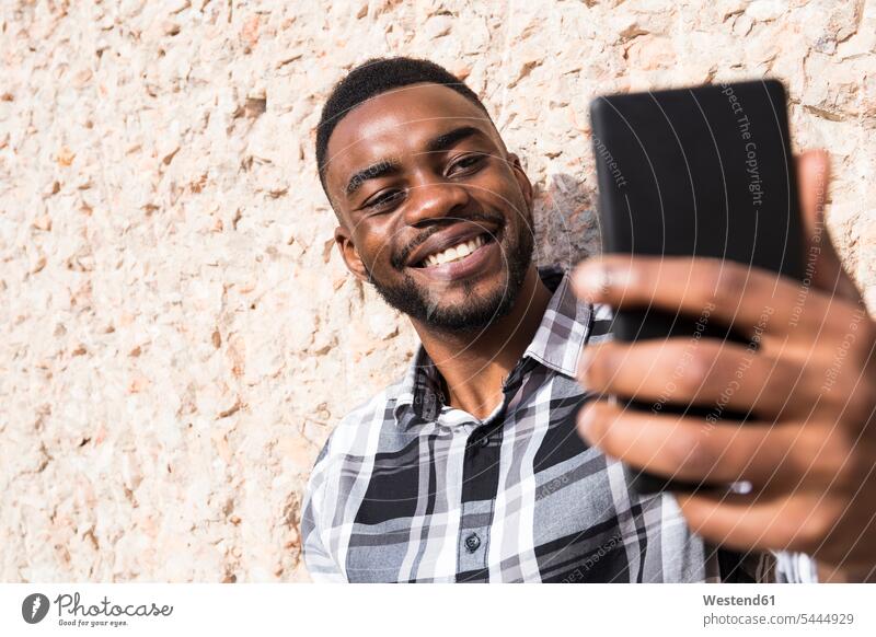 Portrait of smiling young man taking selfie with cell phone men males Selfie Selfies Smartphone iPhone Smartphones Adults grown-ups grownups adult people