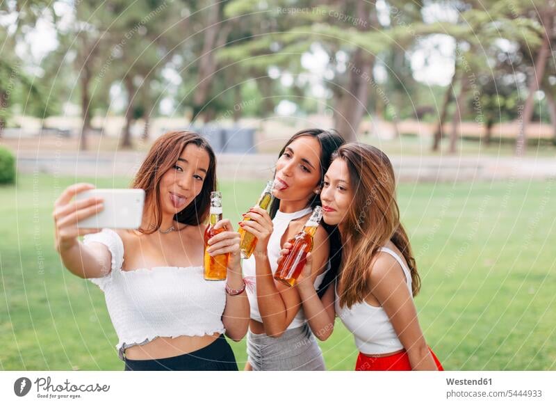 Playful friends in a park drinking beer and taking a selfie parks Beer Beers Ale holding female friends Alcohol alcoholic beverage Alcoholic Drink