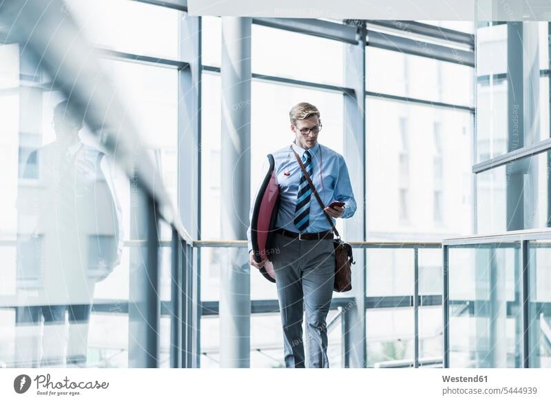 Businessman with cell phone carrying surfboard in office surfboards mobile phone mobiles mobile phones Cellphone cell phones Business man Businessmen