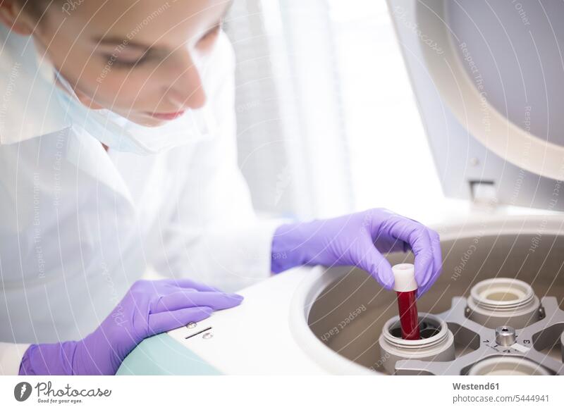 Scientist in lab putting blood sample into centrifuge female scientists swatch Swatches Samples examining checking examine laboratory science sciences