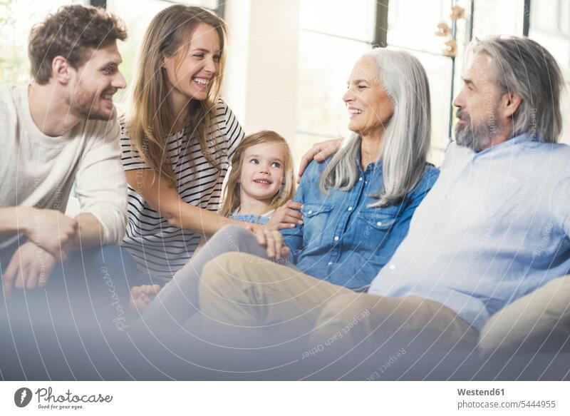 Extended family sitting on couch, smiling happily happiness happy families cozy sociable comfortable cosy settee sofa sofas couches settees together Seated home
