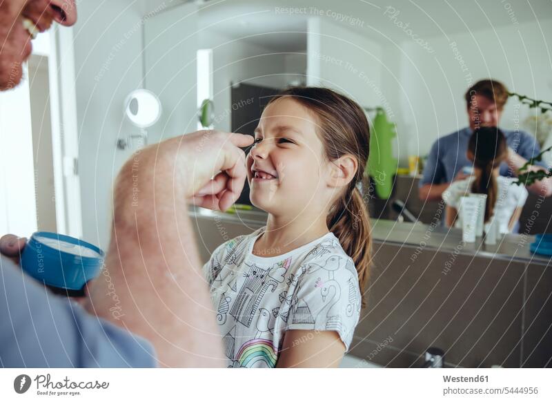 Father putting facial cream on daughter’s face daughters creams cosmetic cream applying father pa fathers daddy dads papa child children family families people