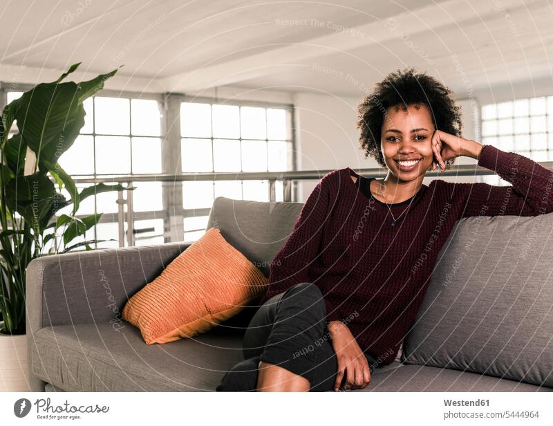 Portrait of smiling young woman sitting on couch smile females women relaxed relaxation Seated Adults grown-ups grownups adult people persons human being humans