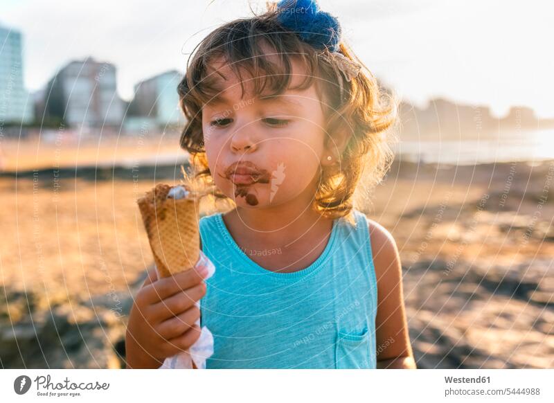 Portrait of little girl eating chocolate icecream on the beach at sunset females girls portrait portraits child children kid kids people persons human being