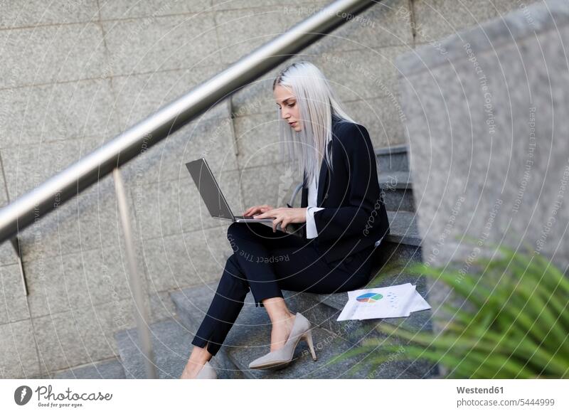 Young businesswoman sitting on stairs in the city using laptop Laptop Computers laptops notebook businesswomen business woman business women stairway females
