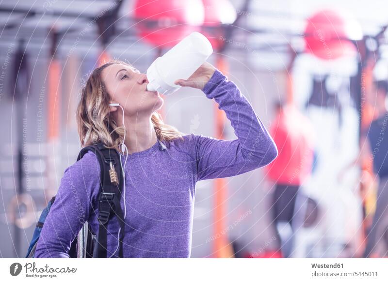 Young woman taking a refreshment break in gym gyms Health Club females women drinking exercising exercise training practising fitness sport sports Adults