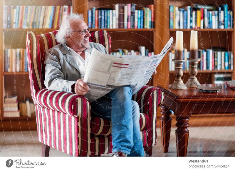 Senior man sitting in library, reading newpaper Seated senior men senior man elder man elder men senior citizen retirement home nursing home newspaper