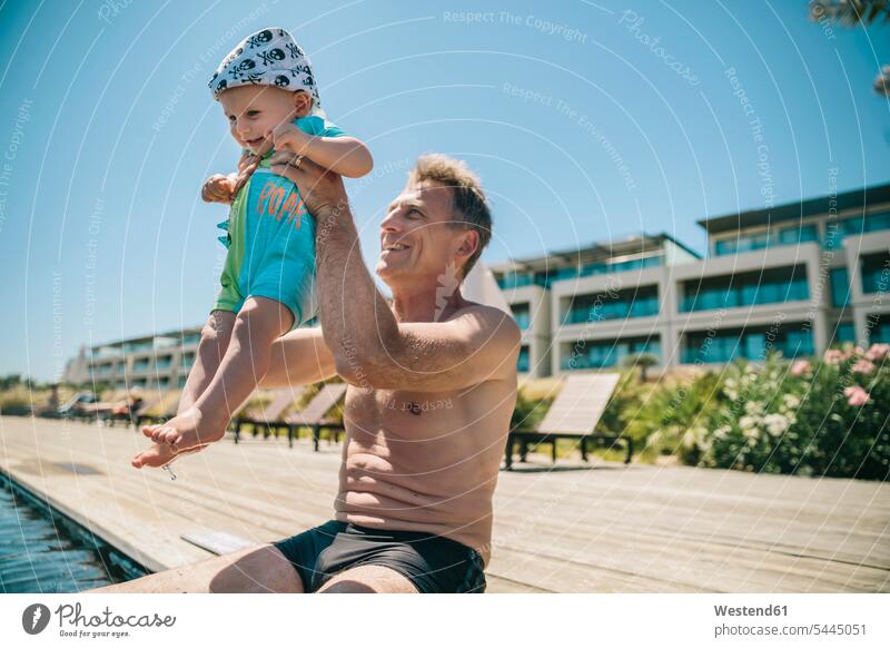 Happy father and baby son at the poolside during summer vacation infants nurselings babies Holidays happiness happy swimming pool swimming pools pool edge