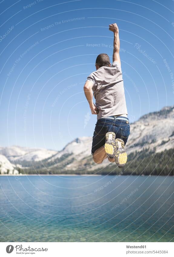 USA, California, Yosemite National Park, back view of man jumping in the air at mountain lake men males lakes Leaping Adults grown-ups grownups adult people