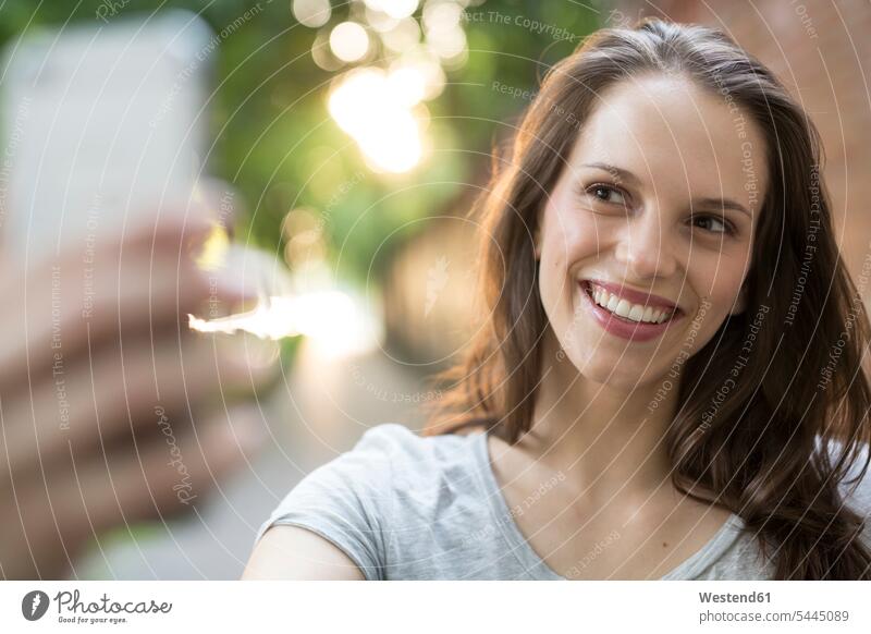 Portrait of happy young woman outdoors taking a selfie smiling smile portrait portraits mobile phone mobiles mobile phones Cellphone cell phone cell phones