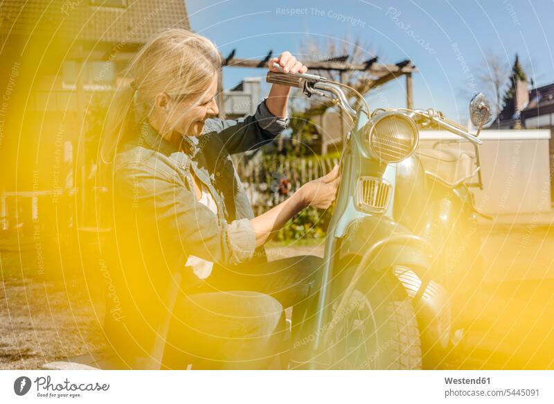 Smiling woman with vintage motorcycle females women motorbike Motor Cycle smiling smile Adults grown-ups grownups adult people persons human being humans