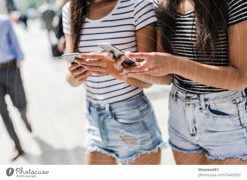 Two young women holding cell phones in the city female friends mobile phone mobiles mobile phones Cellphone mate friendship telephones communication