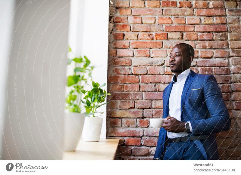 Businessman with cup of coffee at brick wall by the window Business man Businessmen Business men Coffee business people businesspeople business world