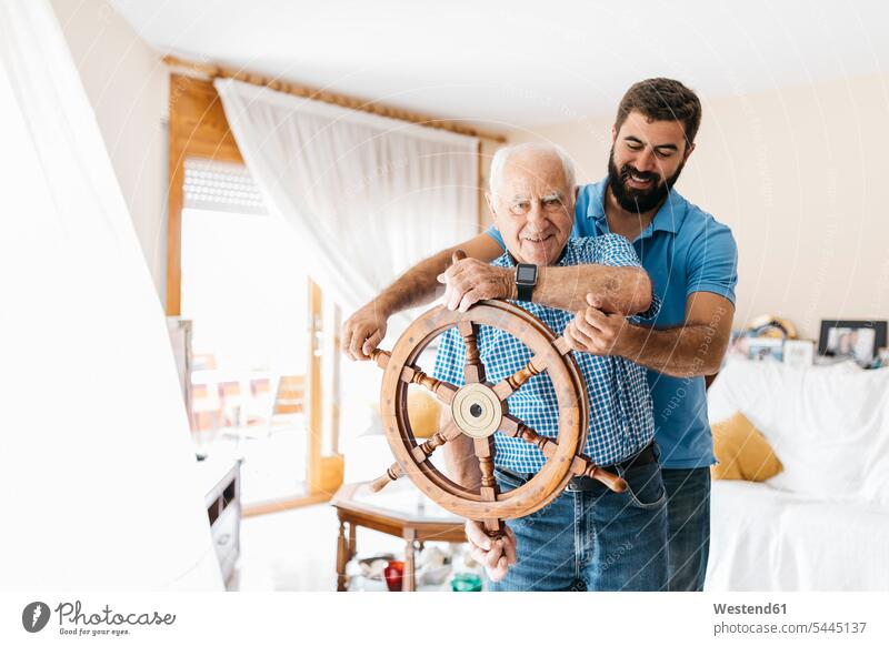 Portrait of grandfather and adult son with helm in the living room grandson grandsons senior men senior man elder man elder men senior citizen grandpas