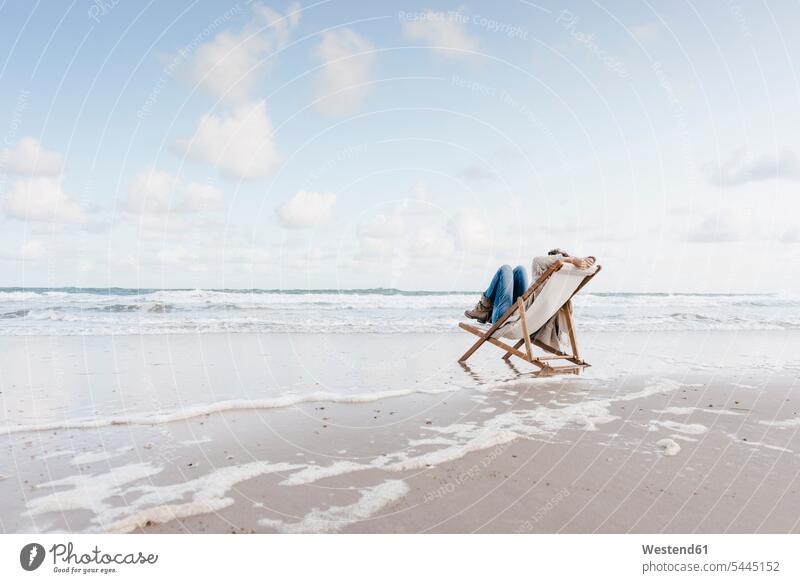 Woman sitting on deckchair on the beach beaches Seated woman females women Adults grown-ups grownups adult people persons human being humans human beings