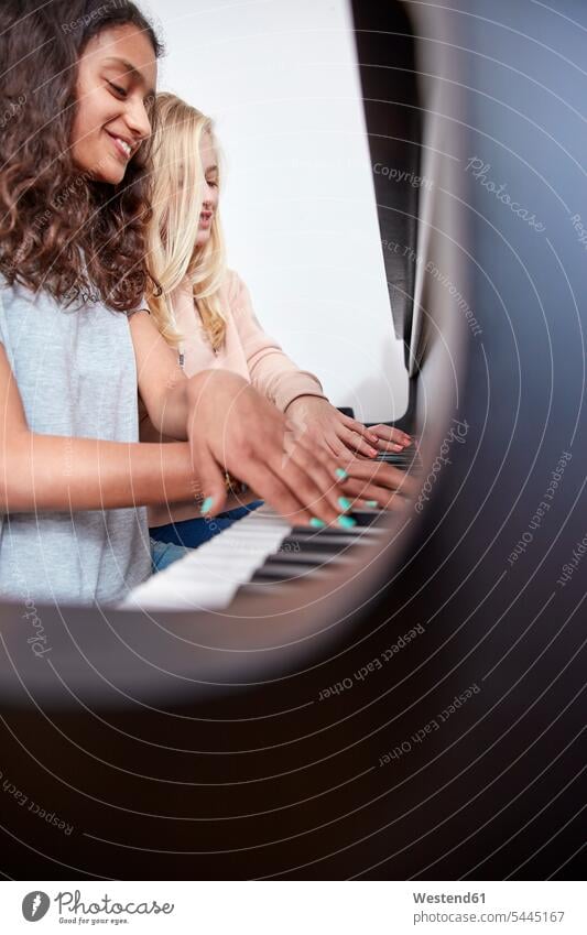 Two girls playing piano together pianos females smiling smile music keyboard instrument musical instrument musical instruments Instruments child children kid