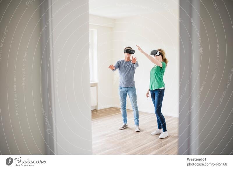 Young couple discussing in empty apartment wearing VR glasses Virtual Reality Glasses Virtual-Reality Glasses virtual reality headset vr headset vr goggles