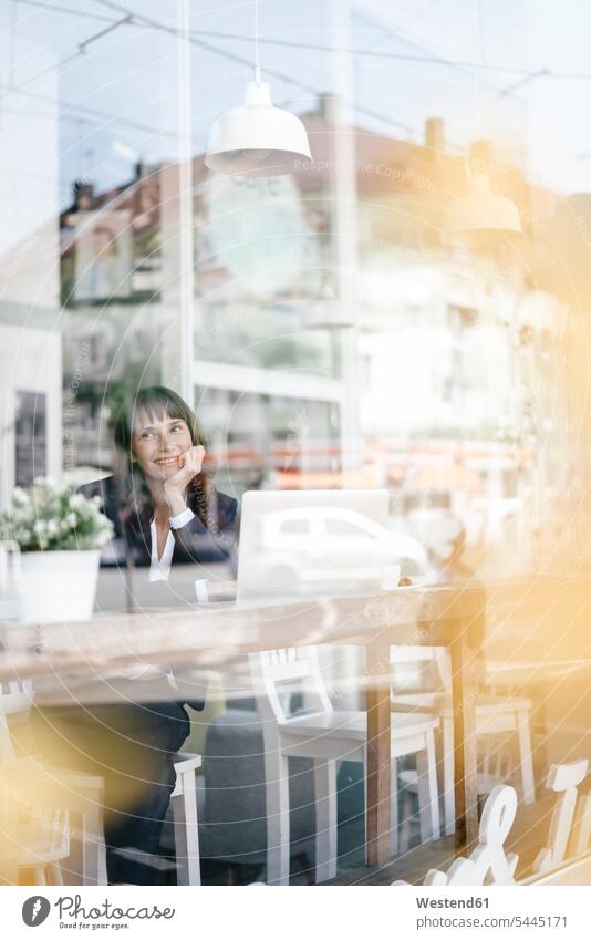 Businesswoman sitting in cafe with laptop, smiling and thinking Seated businesswoman businesswomen business woman business women smile happiness happy