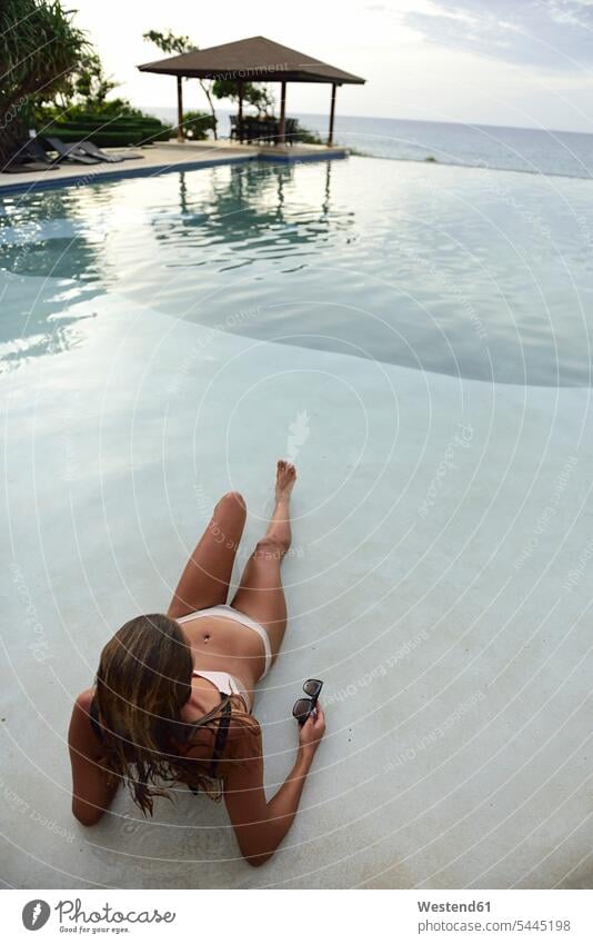 Young woman lying at swimming pool laying down lie lying down females women pools swimming pools Adults grown-ups grownups adult people persons human being