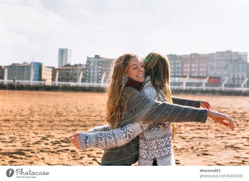 Two friends giving each other a hug on the beach mate female friend beaches smile human human being human beings humans person persons Teen teenager Teens