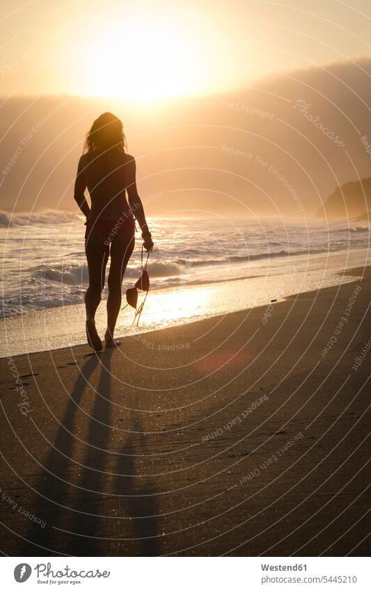 Mexico, Riviera Nayarit, silhouette of woman walking into the sunset at a beach while holding her bikini top sunsets sundown females women beaches sea ocean