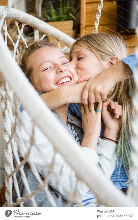 Girl hugging and kissing her best friend in a hanging chair embracing embrace Embracement female friends laughing Laughter bff best friends girl females girls