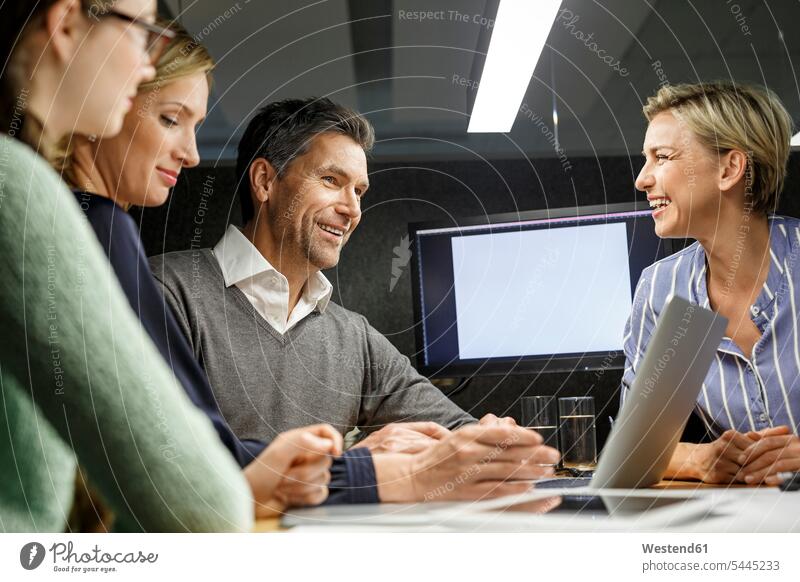 Colleagues with laptop having a meeting in meeting box Laptop Computers laptops notebook smiling smile business people businesspeople office offices office room