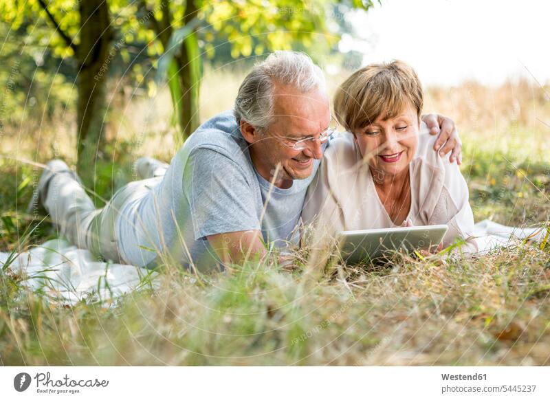 Happy senior couple with tablet lying in meadow smiling smile digitizer Tablet Computer Tablet PC Tablet Computers iPad Digital Tablet digital tablets