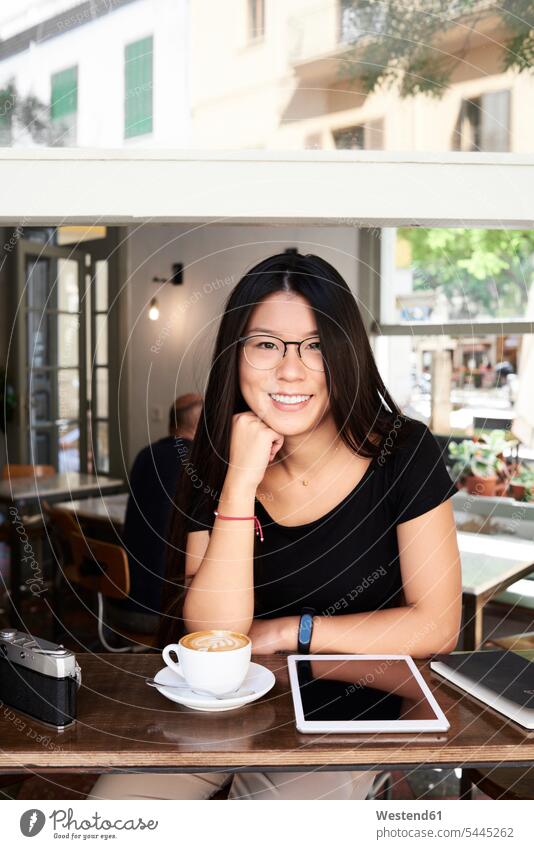 Portrait of an asian young woman smiling at camera in a coffee shop content pleased female tourist sitting Seated females women female Asian female Asians cafe