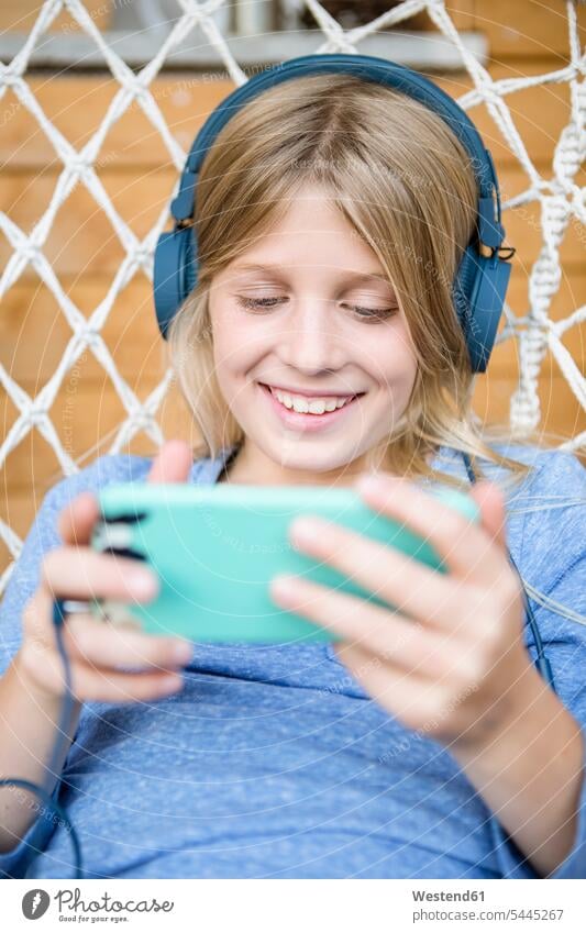 Portrait of happy girl with headphones and smartphone in a hanging chair headset females girls happiness Smartphone iPhone Smartphones child children kid kids