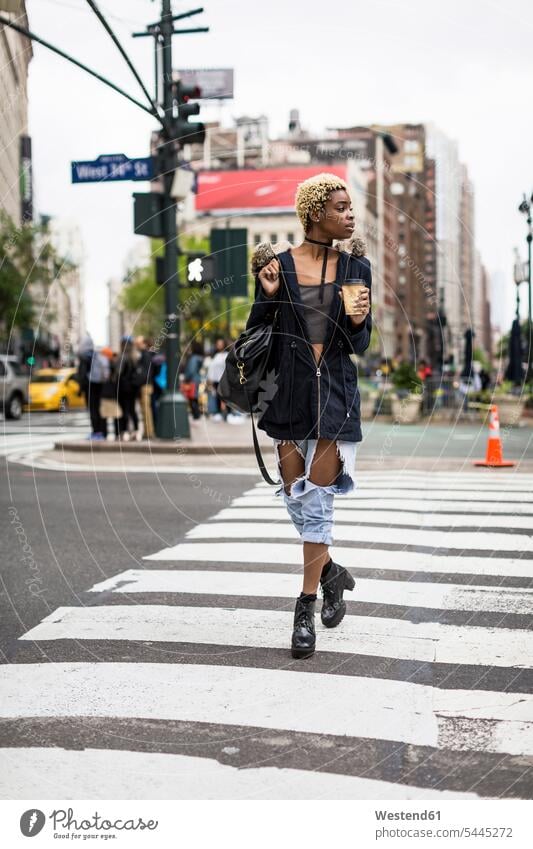 USA, New York City, fashionable young woman with coffee to go crossing the street road streets roads Coffee to Go takeaway coffee females women walking going