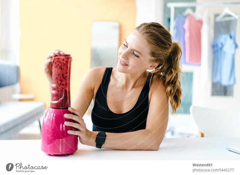 Smiling young woman in sportswear preparing a smoothie smiling smile Sportswear Activewear Sport Clothes Sports Clothes Sports Wear Sports Clothing