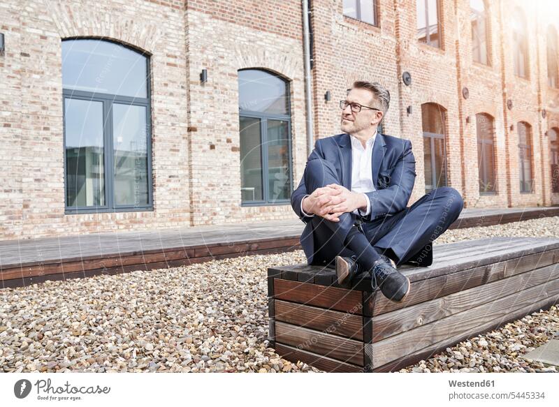 Businessman wearing blue suit sitting on bench Business man Businessmen Business men business people businesspeople business world business life males