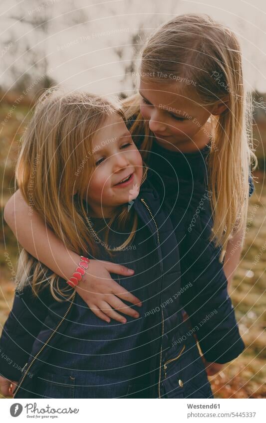 Girl hugging her sister outdoors sisters girl females girls smiling smile embracing embrace Embracement siblings brother and sister brothers and sisters family