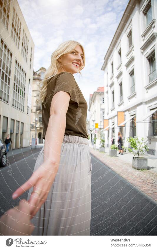 Smiling blond woman holding hands on the street females women Adults grown-ups grownups adult people persons human being humans human beings blond hair