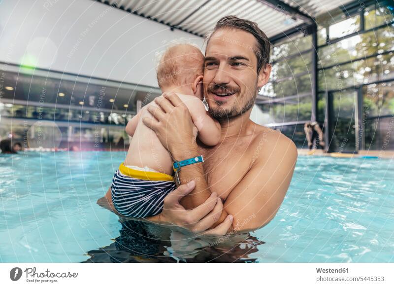 Father holding baby in indoor swimming pool indoor swimming pools father pa fathers daddy dads papa smiling smile swimming bath infants nurselings babies