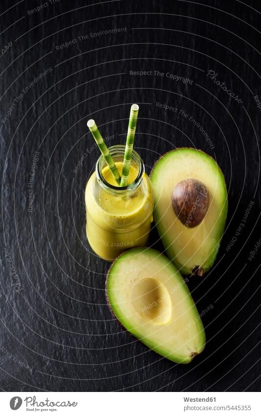 Glass bottle of avocado smoothie and sliced avocado on slate overhead view from above top view Overhead Overhead Shot View From Above Avocado Avocados
