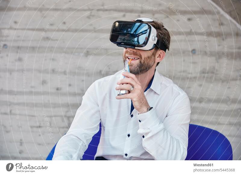 Man sitting on chair wearing VR glasses Seated smiling smile Businessman Business man Businessmen Business men males Virtual Reality Glasses