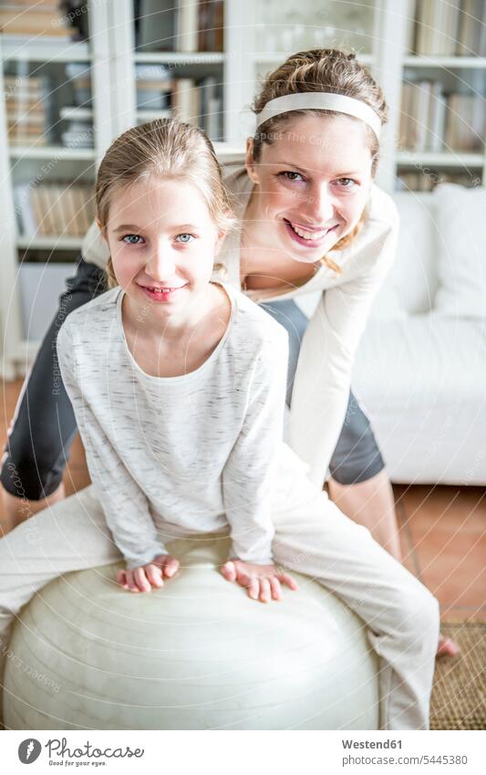 Mother and daughter with fitness ball at home gymnastics smiling smile family families mother mommy mothers ma mummy mama daughters Fitness Ball Fitness Balls