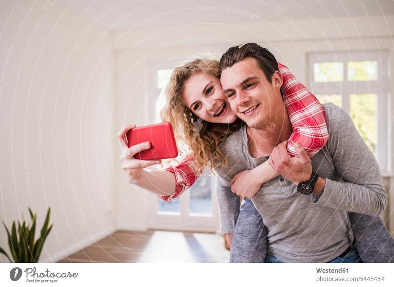Happy young couple in new home taking a selfie Fun having fun funny twosomes partnership couples mobile phone mobiles mobile phones Cellphone cell phone