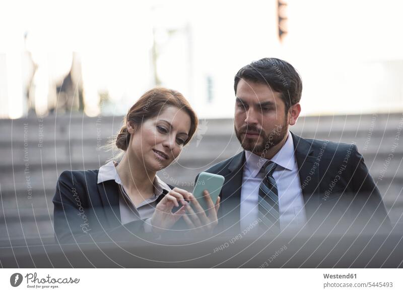 Businesswoman sharing cell phone with colleague colleagues talking speaking mobile phone mobiles mobile phones Cellphone cell phones telephones communication