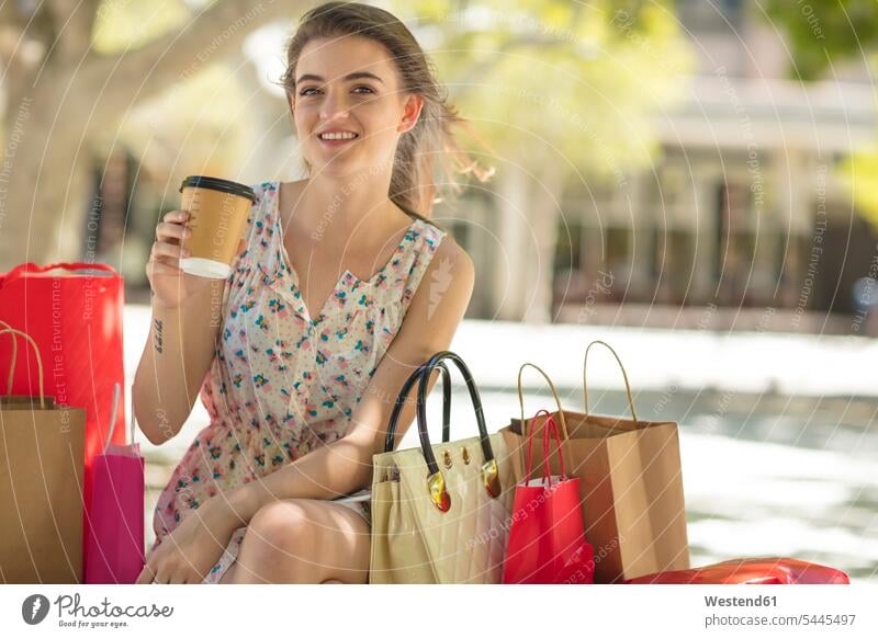 Smiling young woman with shopping bag and takeaway coffee Coffee smiling smile happiness happy shopping-bag shopping-bags shopping bags females women Drink