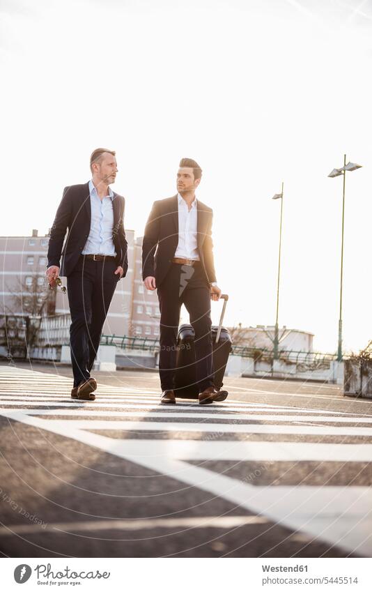 Two businessmen walking on parking place at sunset Businessman Business man Businessmen Business men business people businesspeople business world business life