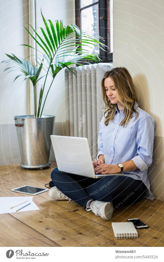 Woman sitting on the floor at home using laptop Seated Laptop Computers laptops notebook woman females women use floors computer computers Adults grown-ups