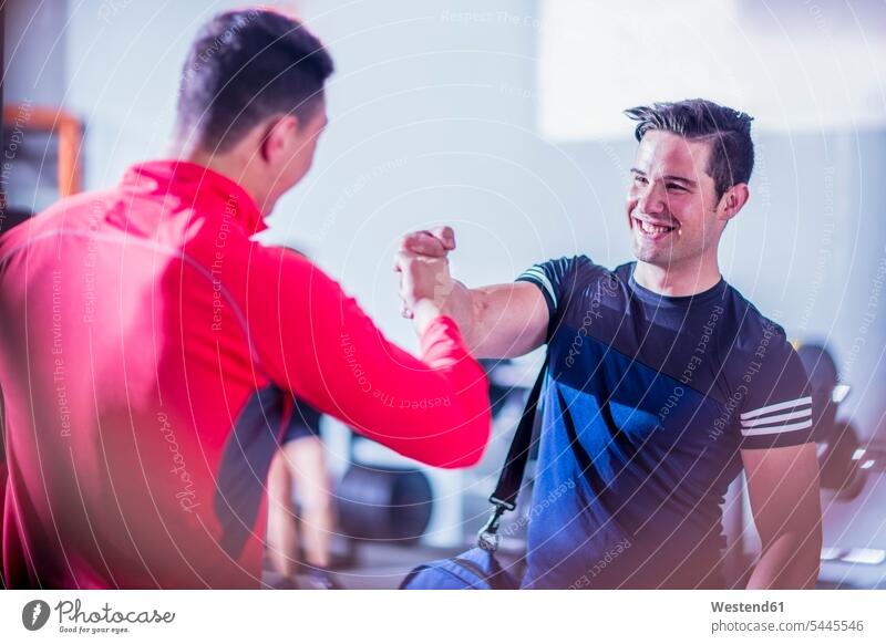Two young men shaking hands in gym smiling smile exercising exercise training practising friends gyms Health Club friendship fitness sport sports Fitness