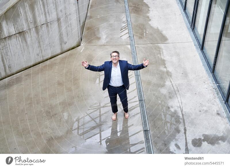 Smiling businessman standing barefoot in a puddle looking up Businessman Business man Businessmen Business men puddles pool business people businesspeople