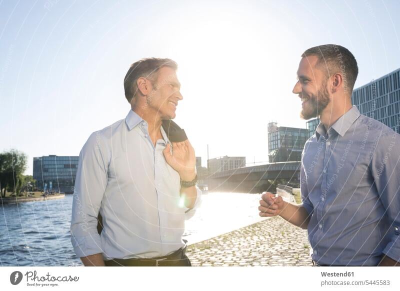 Two confident businessmen talking at the riverbank colleagues smiling smile speaking Businessman Business man Businessmen Business men business people